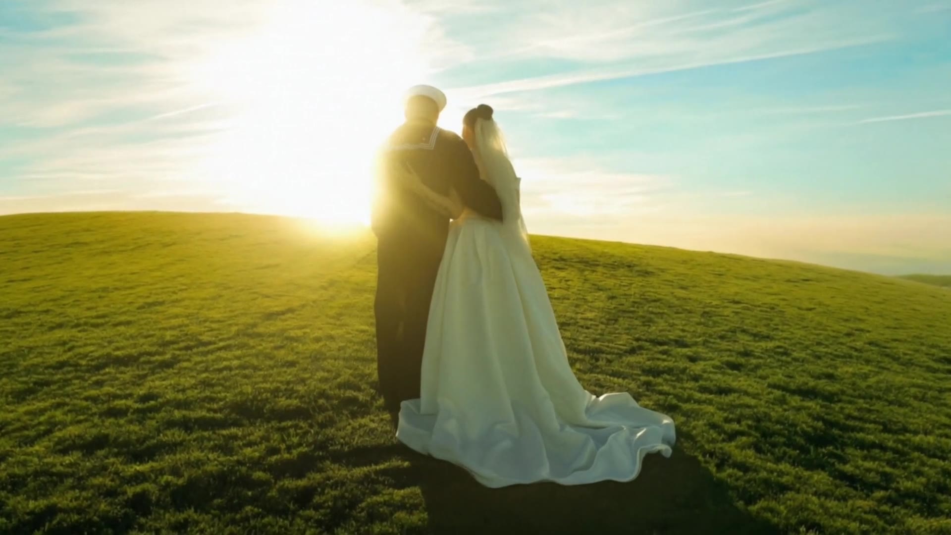 Newlyweds holding each other on a hill as the evening sun pours over them